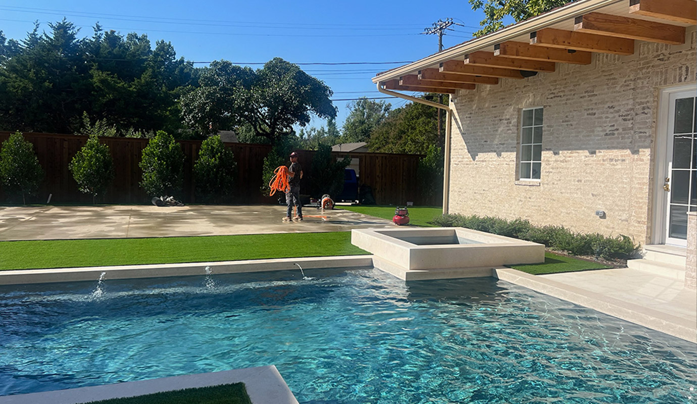 A backyard with an artificial turf lawn installed near a swimming pool