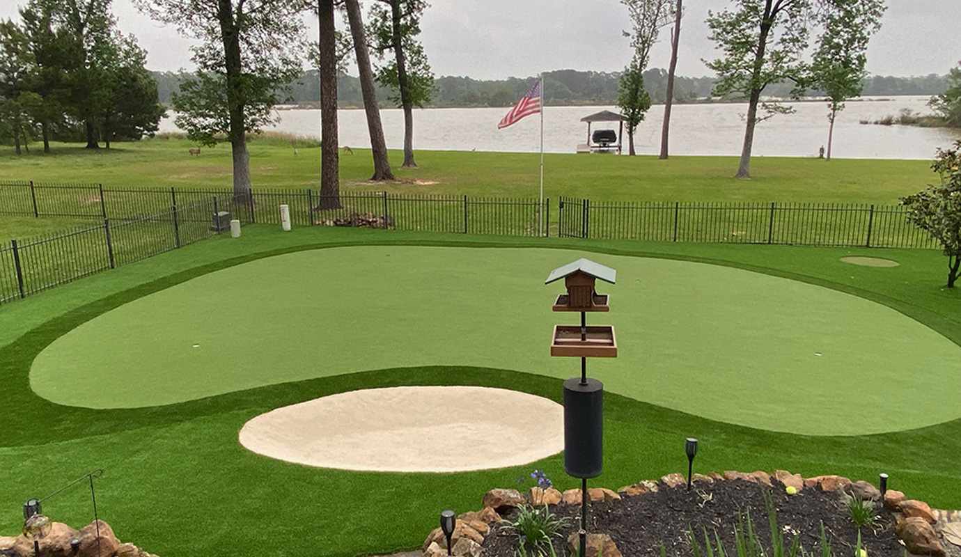 A backyard with an artificial grass putting green designed for golf practice