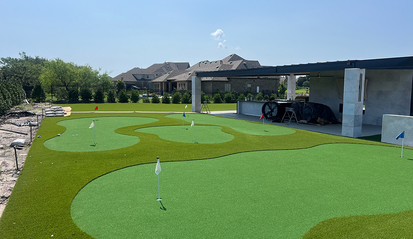 A backyard putting green with artificial turf, multiple holes and flags