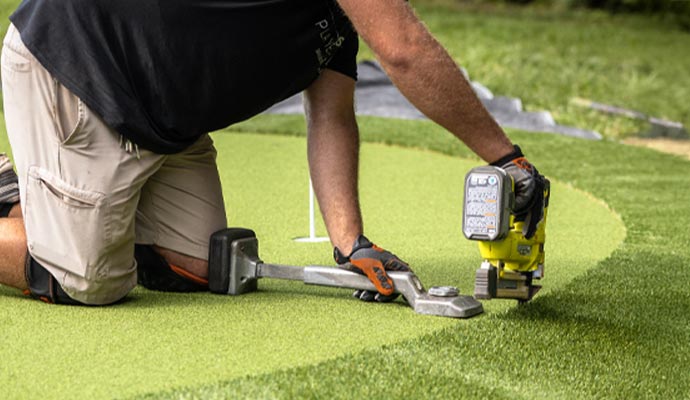 A professional installing artificial turf with equipment