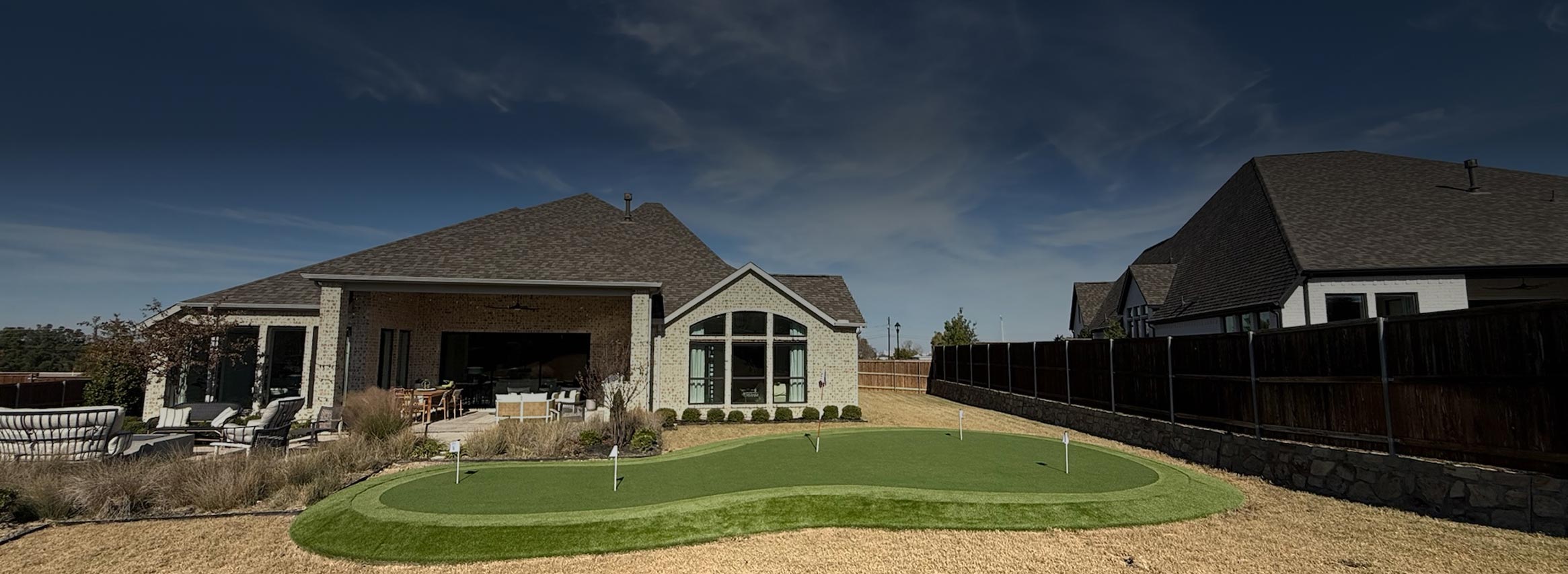 A residential backyard with artificial grass putting green for golf practice
