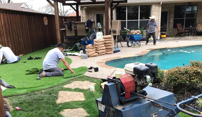 Professional team installing artificial turf on residential pool area